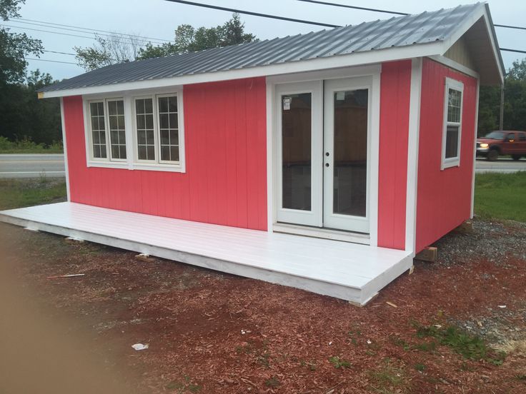 a small red and white shed sitting on the side of a road