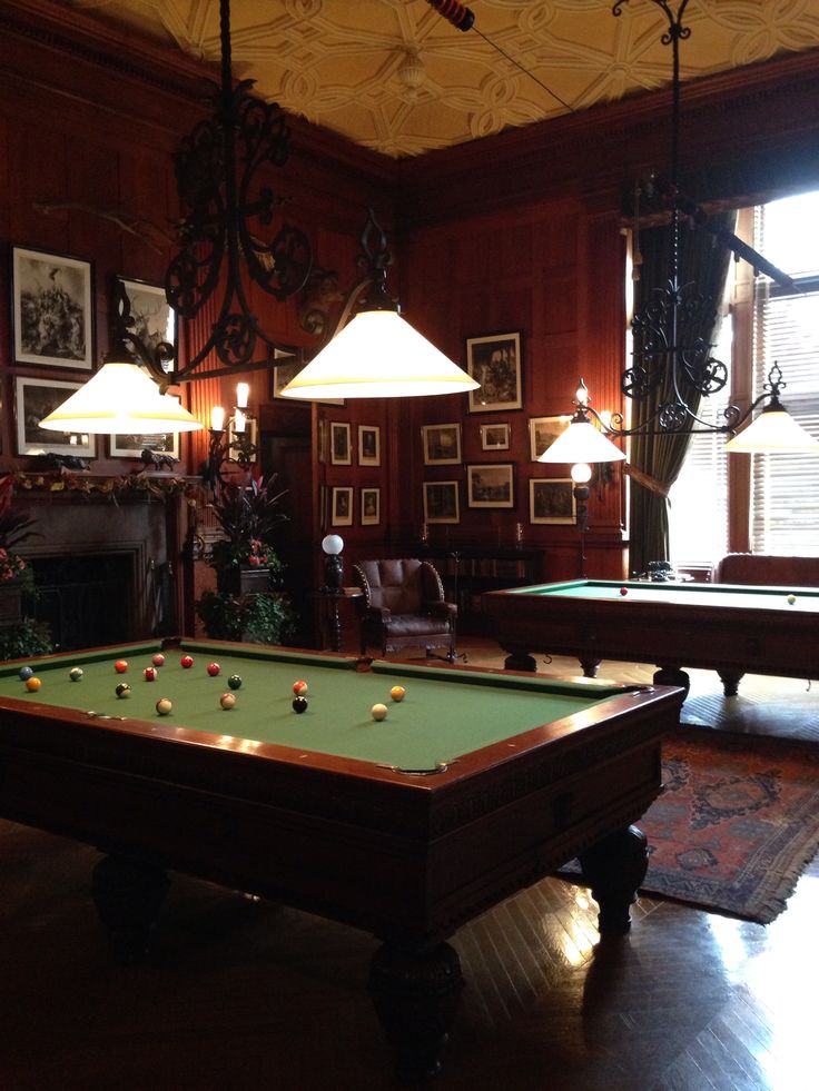 a pool table in the middle of a living room with two lamps on either side