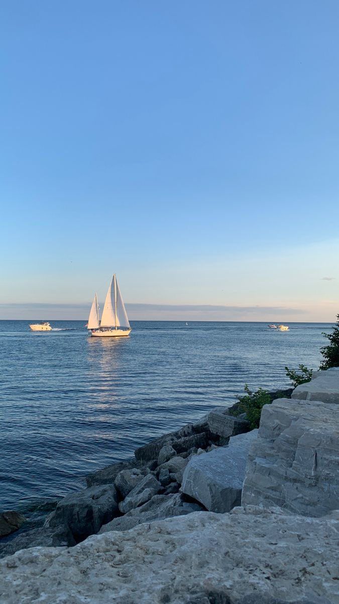 a sailboat is out on the water near some rocks