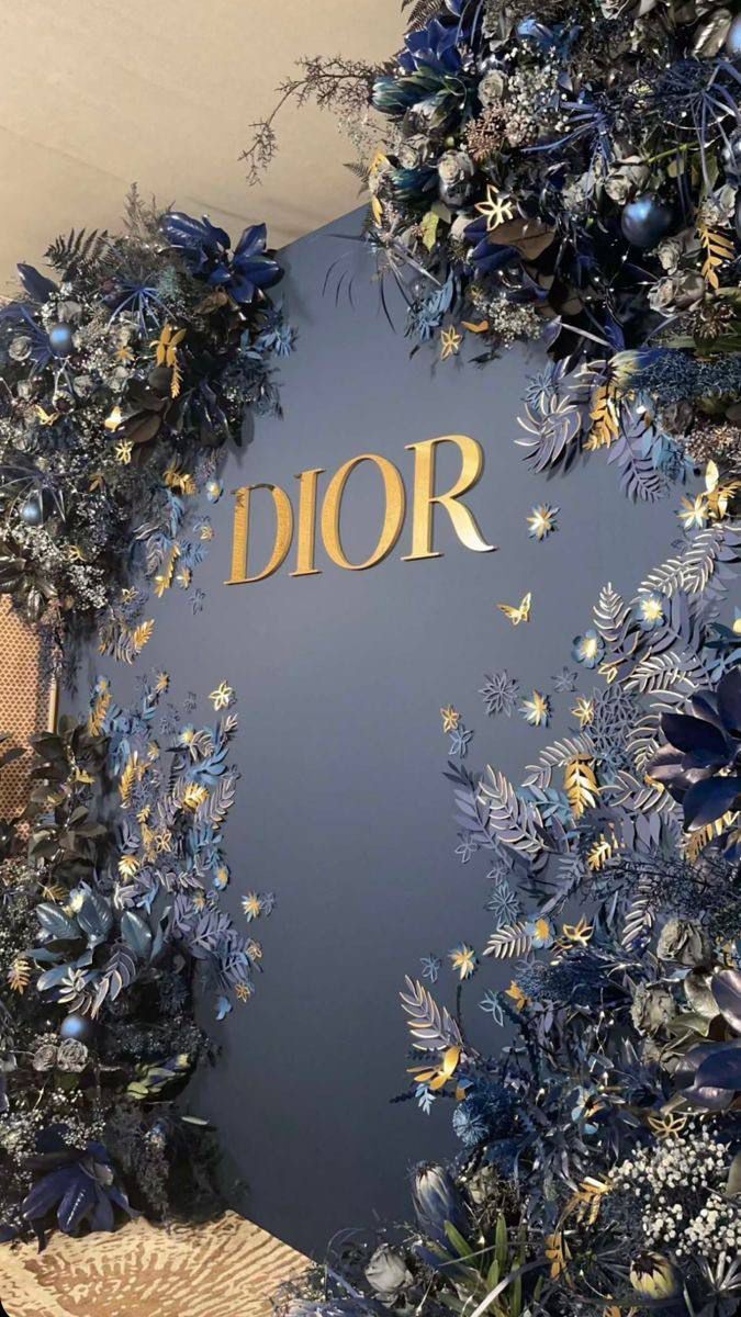 the dior logo is surrounded by blue and gold flowers, leaves and butterflies on a wall