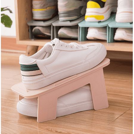 a pair of white tennis shoes sitting on top of a wooden bench in front of shelves