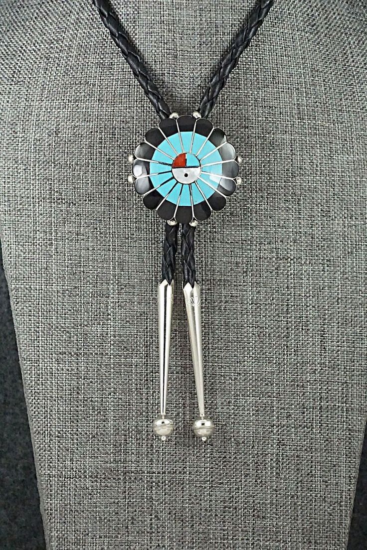 This mother of pearl, turquoise, onyx, coral and sterling silver inlay Zuni Sun Face shaped bolo tie was made by Navajo silversmith Denise Siutza. The back is signed FDS and stamped sterling.Tie Length: 22 1/2"Bolo Length: 1 5/8"Bolo Width: 1 5/8"Tips:Length: 2 1/4"Width: 3/8"Free shipping on all orders! We ship with USPS and always include tracking. All orders ship within a day of payment.Returns are accepted up to 30 days after you receive your order. Just send us a message. Our shop offers ca Handmade Sterling Silver Bolo Tie As Gift, Blue Lariat Bolo Tie For Gift, Unique Silver Bolo Ties As Gift, Handmade Silver Bolo Tie As A Gift, Unique Silver Bolo Ties For Gift, Handmade Silver Bolo Tie For Gift, Unique Silver Bolo Tie As A Gift, Unique Silver Bolo Tie For Gift, Adjustable Sterling Silver Bolo Tie For Gifts