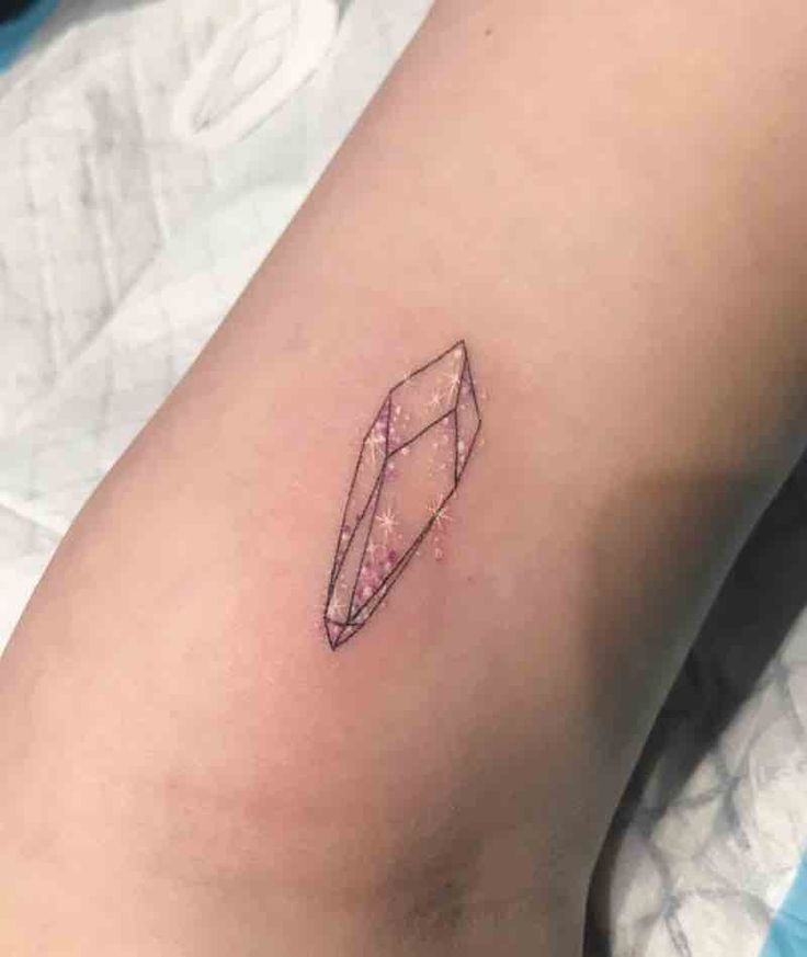 a small diamond tattoo on the right arm and leg, with pink glitters around it