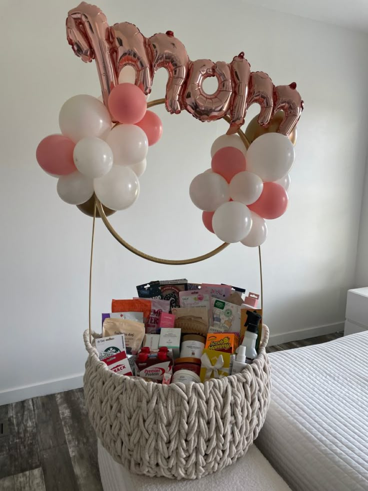 a basket filled with balloons and the word mom spelled out in large letters on top