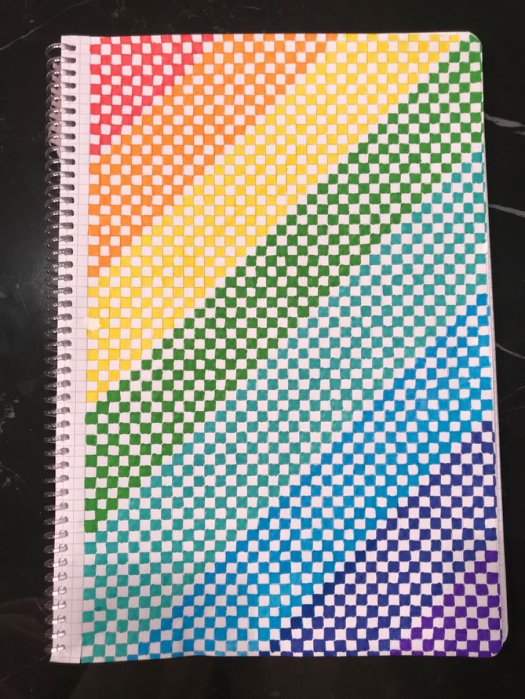 a rainbow colored checkered notebook on a black surface