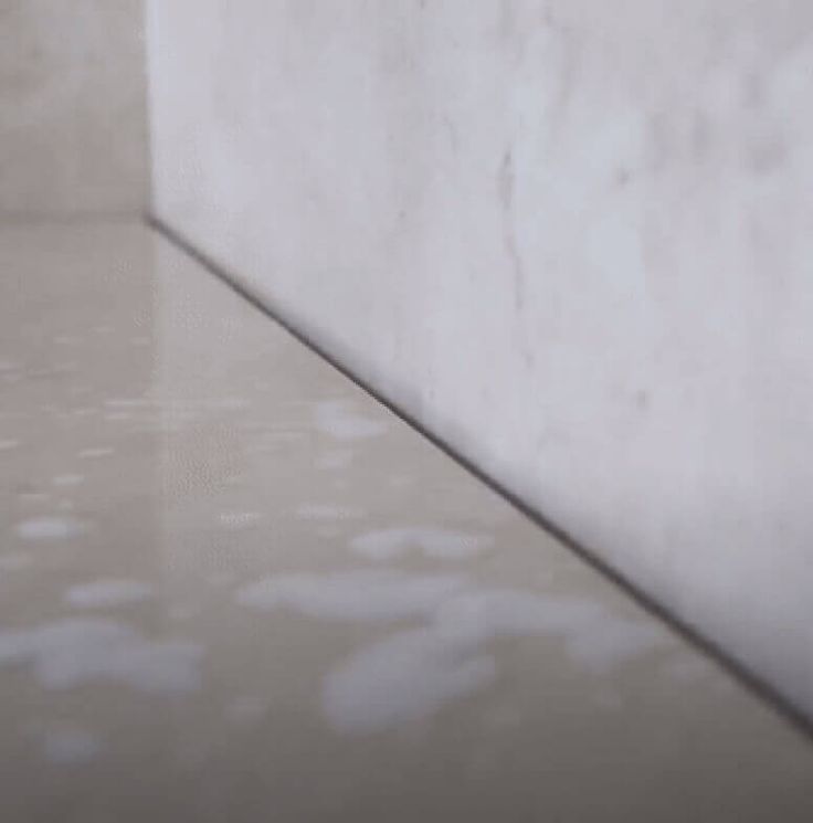 a white toilet sitting next to a wall in a room with tile floors and walls