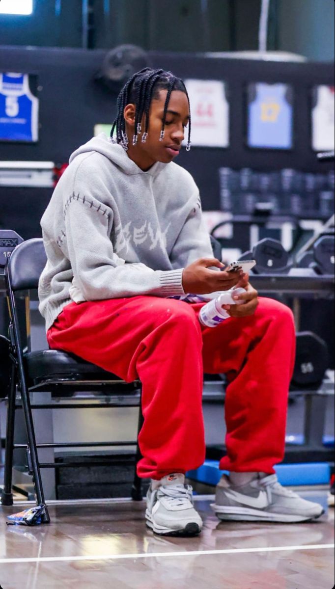 a young man sitting on top of a chair holding a cell phone in his hand