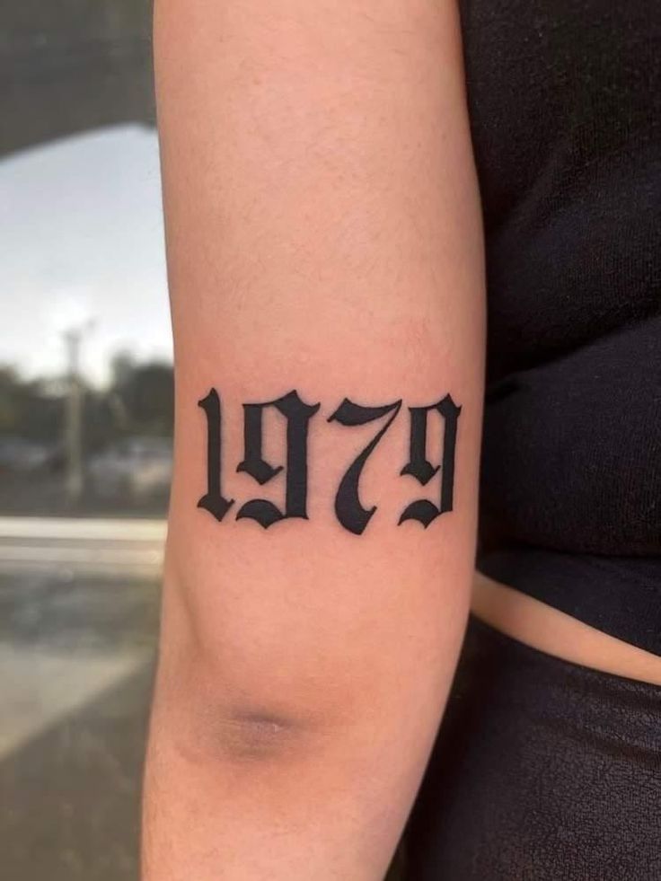 a woman's arm with a tattoo that reads 479 and has the number seventy on it