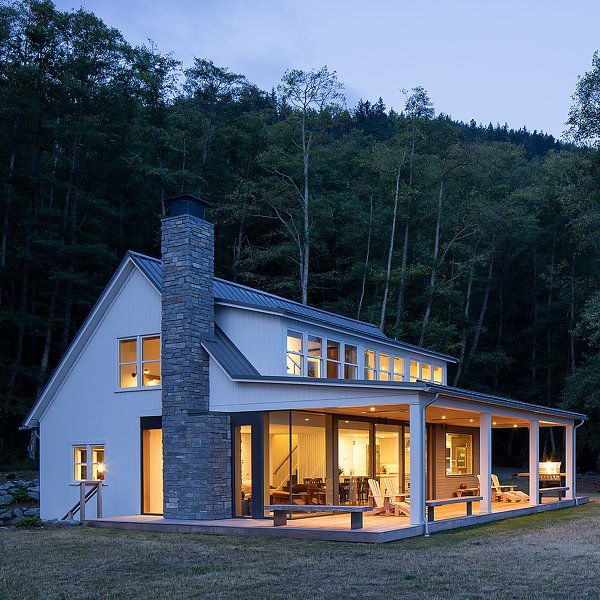 a white house sitting on top of a lush green hillside next to forest at night