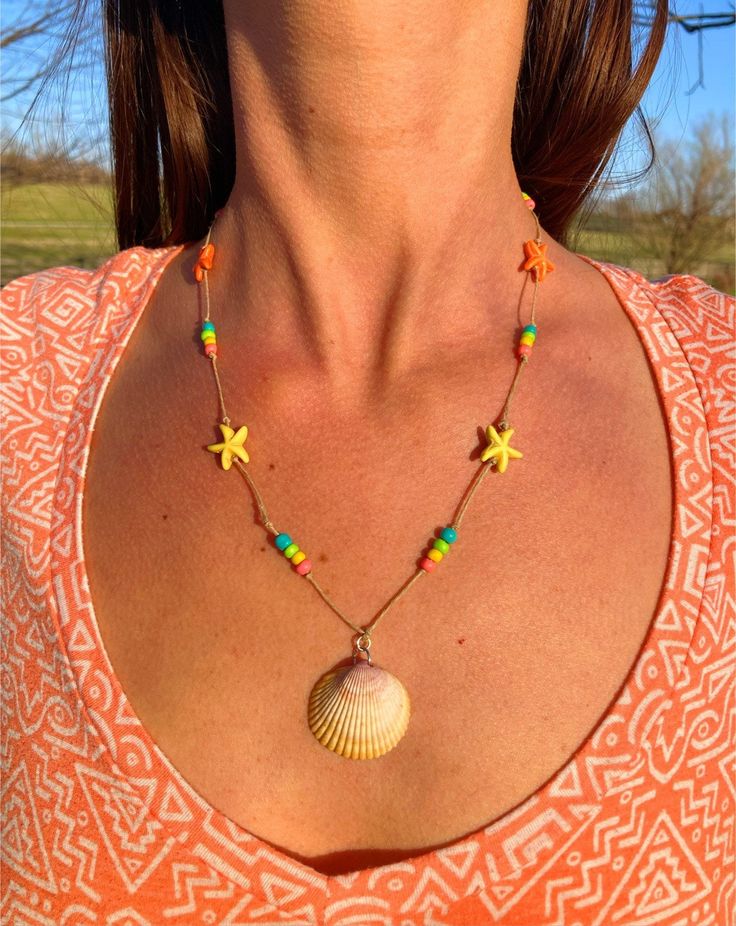 "Wear the beach around your neck with this colorful, beaded boho statement necklace! This necklace is made with a beautiful seashell that was hand-picked directly from the shores of the gulf coast by yours truly 😉 and is embellished with adorable starfish beads and glass beads. The stars and bright colors make it a perfect choice for your next 4th of July party!  It is strung on durable, undyed hemp cord for a natural, beachy look and feel. The center shell measures approximately 1.25\" tall an Beachy Shell Necklaces For Summer, Starfish Charm Necklace For Beach Vacation, Summer Vacation Beaded Necklace With Starfish Charm, Vacation Necklace With Starfish Charm For Beach Season, Beach Season Vacation Necklace With Starfish Charm, Beachy Shell-shaped Necklaces For Summer, Beach Season Starfish Charm Necklace For Vacation, Hippie Multicolor Beach Necklaces, Coastal Strand Necklace For Summer