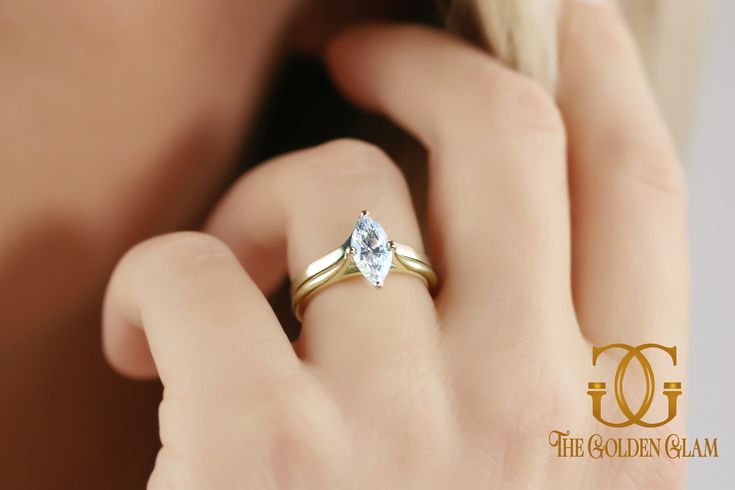 a close up of a person wearing a gold ring with a white diamond on it