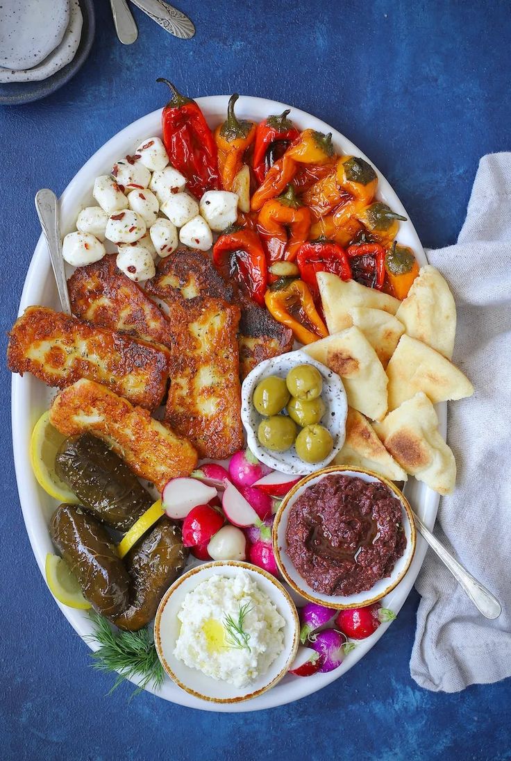 a white plate topped with meat and veggies next to sauces on a blue table