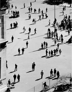 black and white photograph of people walking around in the city square, looking down on them