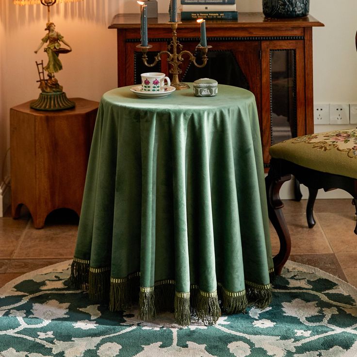 a green table cloth on top of a round table in a living room with two candles