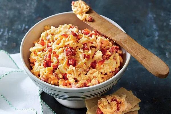 a bowl filled with macaroni and cheese on top of a table next to crackers