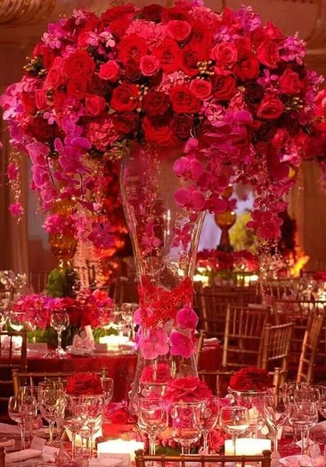 a tall vase filled with lots of pink flowers sitting on top of a dining room table