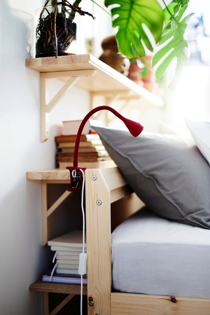 a bed with a plant on top of it next to a pillow and some books