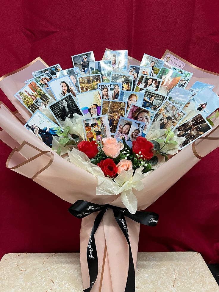 a bouquet of flowers with pictures on the front and back of it, sitting on a table