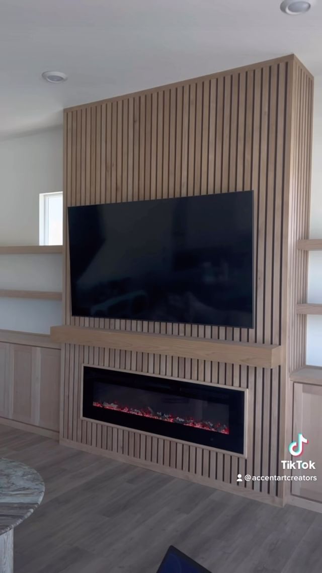 a living room with a large television mounted on the wall and built - in fireplace