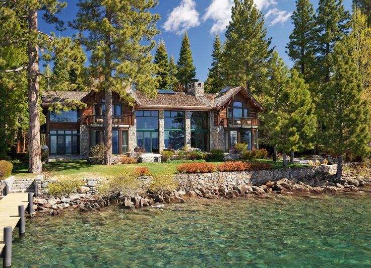 a large house sitting on top of a lake next to a forest