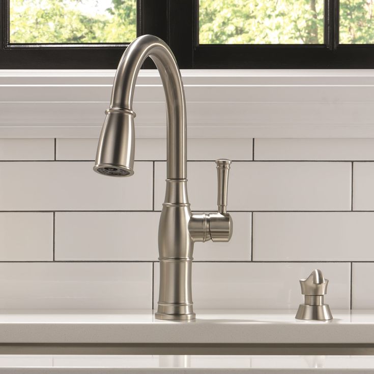 a kitchen sink with a faucet in front of a window and white tile