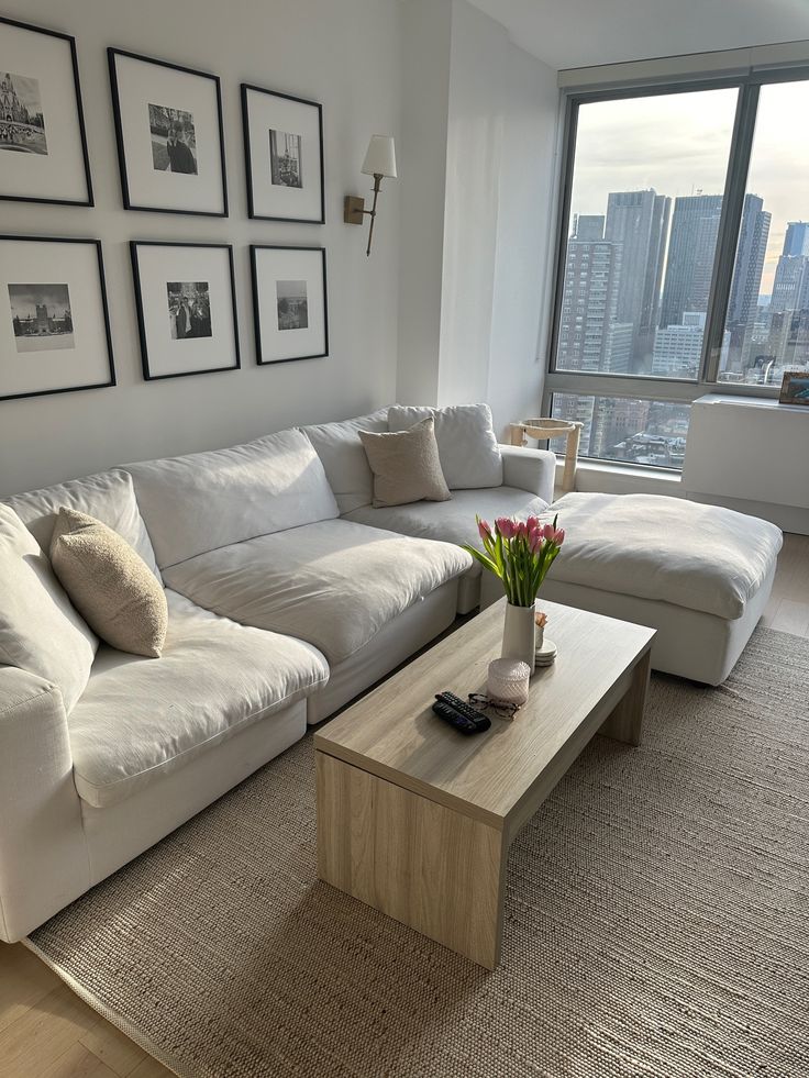 a living room with white couches and pictures on the wall above it, along with a coffee table