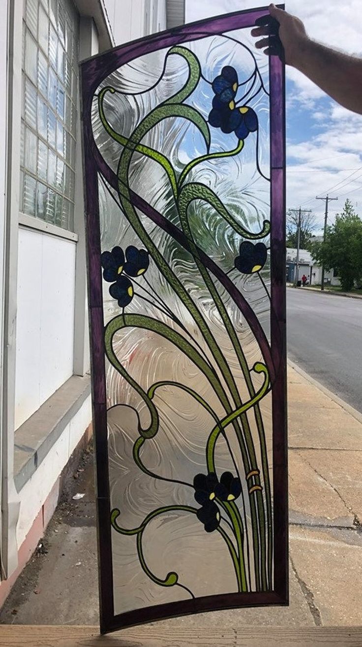 a stained glass window sitting on the side of a building next to a person's hand