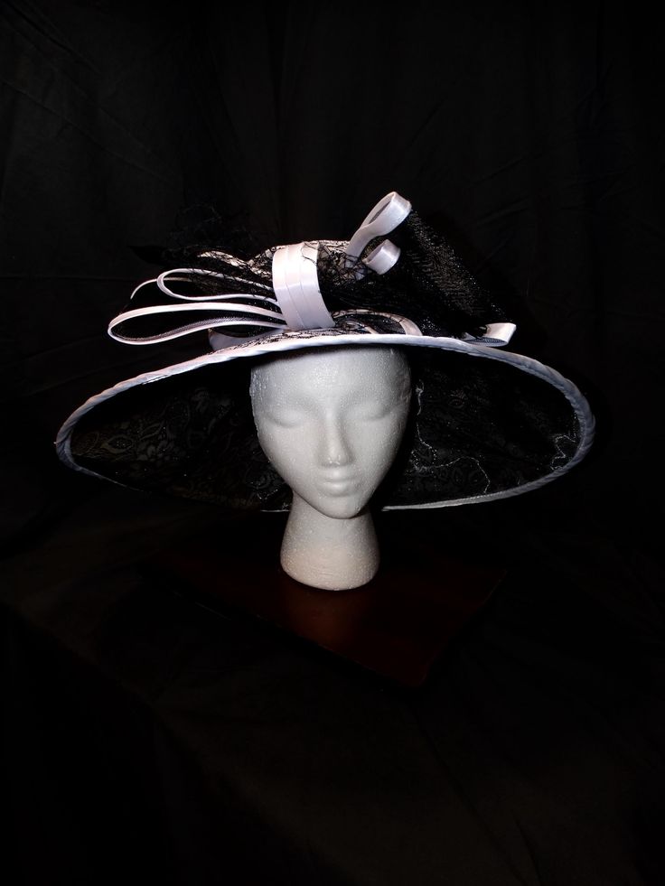 Moonlight Sonata Derby Hat This elegant fascinator is a must-have for any sophisticated wardrobe. Its intricate lace design and dramatic black and white color scheme make it a true statement piece. Intricate Lace Design: A delicate and feminine touch. Dramatic Color Scheme: A striking combination of black and white. Versatile Styling: Can be worn in various ways to suit your style. Perfect for Special Occasions: Ideal for weddings, galas, and other formal events. Make a Statement Today! Elevate your style with this unique accessory--shop now and turn heads at your next event! Elegant High Crown Costume Hats For Races, Elegant Black High Crown Costume Hat, Elegant Brimmed Costume Hats And Headpieces, Elegant High Crown Hat For Kentucky Derby, Elegant Costume Hats For Kentucky Derby With High Crown, High Crown Top Hat For Kentucky Derby Evening, Kentucky Derby Evening Costume Hat With Curved Brim, Elegant Fascinator With Curved Brim For Evening, Elegant High Crown Costume Hats For Evening