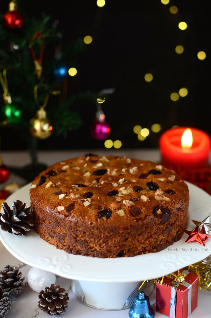 a cake sitting on top of a white plate next to a christmas tree and candles