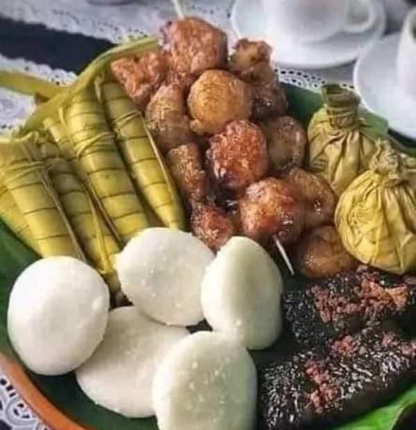 a plate filled with meat and vegetables on top of a lace table cloth next to two cups