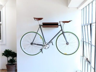 a bike mounted to the wall with bars on it's back and wheels hanging from hooks