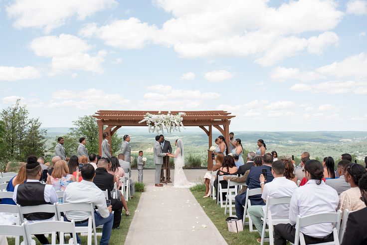 a couple getting married at the end of their wedding ceremony on top of a hill