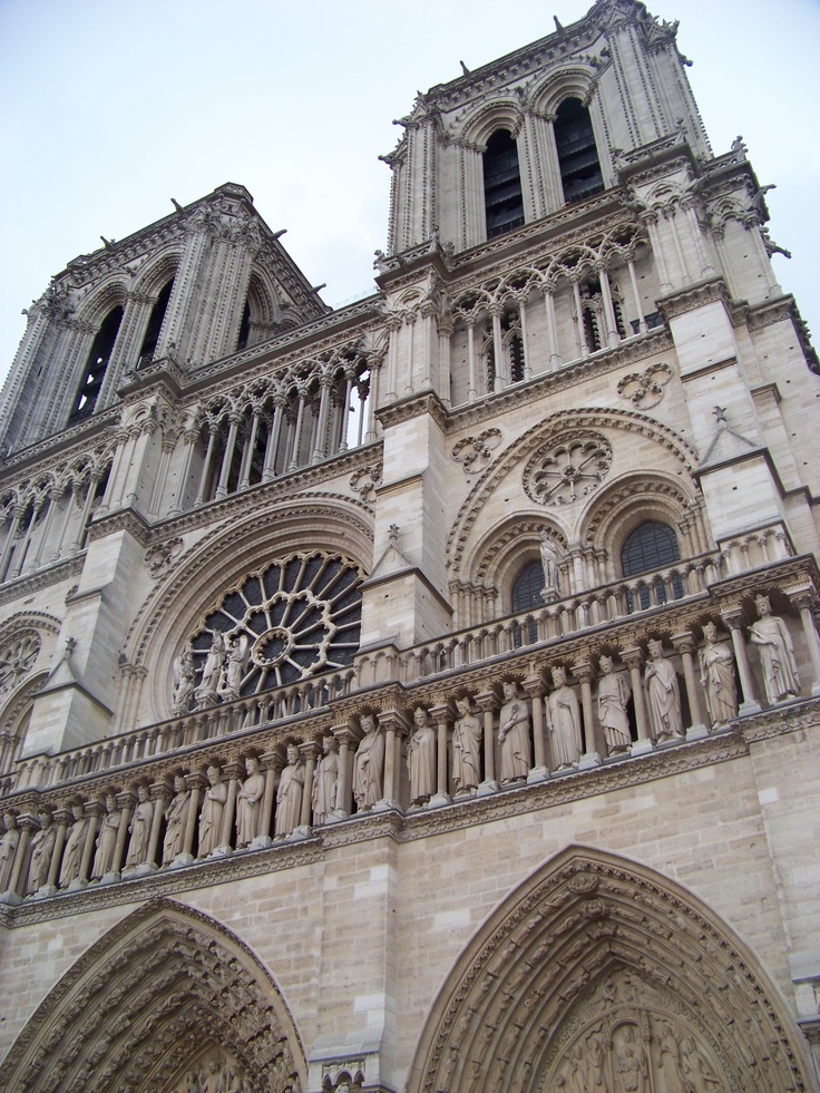 the large cathedral has many statues on it's front wall and is very tall