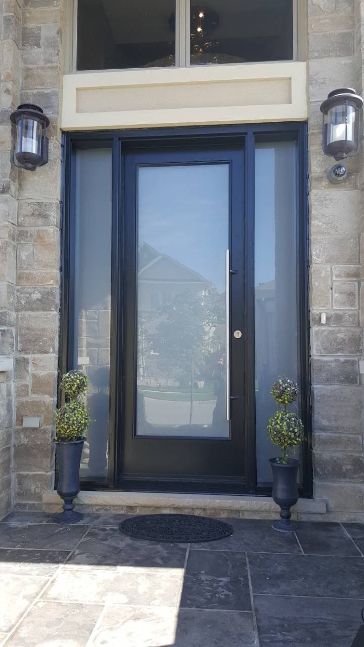 two potted plants are sitting in front of the entrance to a building with glass doors