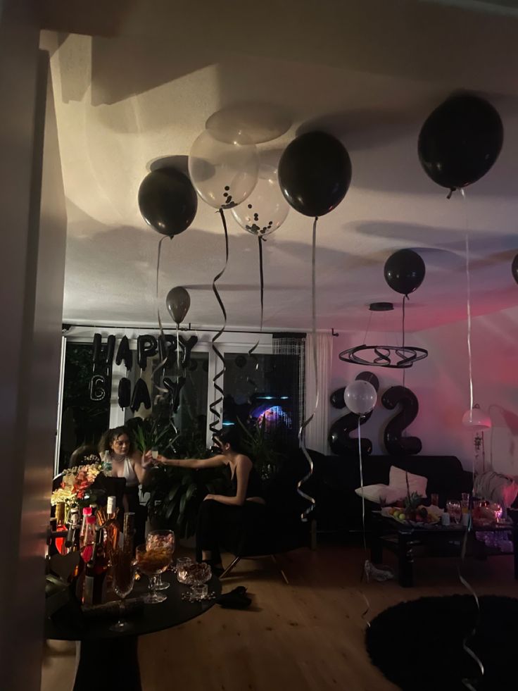 some balloons are hanging from the ceiling in a room with black and white decorations on it