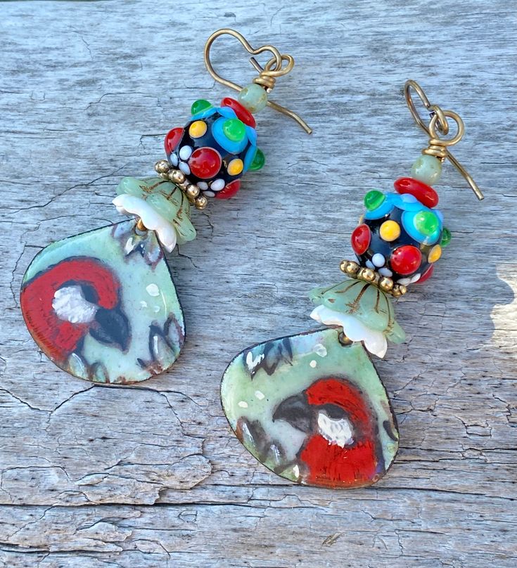 two pairs of colorful earrings on top of a piece of drift wood with bead details