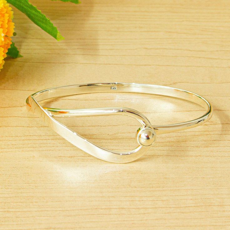 A polished droplet quivers on a shimmering circlet of precious Taxco sterling silver. Working with his son Philip Graeme Watson creates a bracelet of stunning beauty. The simplicity of their modern design takes the shining bangle effortlessly from day to evening from casual to dressy. Silver Bangle Bracelets Unique Modern, Teardrop Shaped Jewelry With Shiny Finish For Anniversary, Shiny Open Band Jewelry Gift, Gift Jewelry With Shiny Finish And Open Band, Adjustable Shiny Round Jewelry, Sterling Silver Teardrop Jewelry With Shiny Finish, Adjustable Teardrop Jewelry With Polished Finish, Adjustable Bracelets With Shiny Finish For Anniversary, Sterling Silver Teardrop Bracelet As Gift