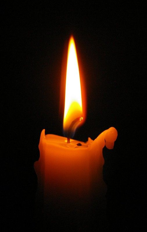 a lit candle in the dark on a black background