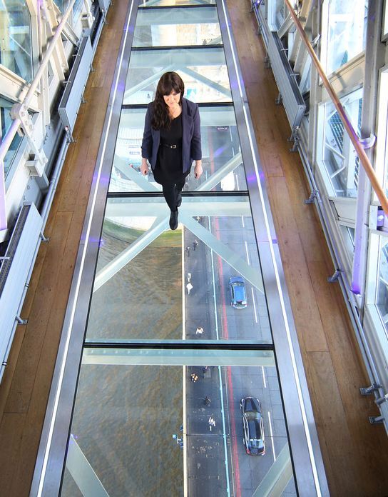 a woman is walking down an escalator in a building that has glass floors