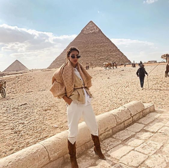 a woman is standing in front of the pyramids