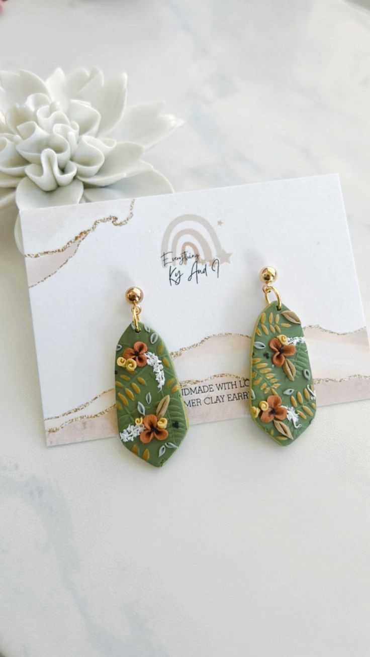 Fun olive green clay earrings with tiny floral and gold painted leaves 1.75 inches gold plaited stainless steal Everyday Hand Painted Dangle Jewelry, Green Botanical Drop Earrings Jewelry, Bohemian Polymer Clay Flower Drop Earrings, Bohemian Flower Drop Earrings In Polymer Clay, Green Bohemian Flower Earrings For Gift, Bohemian Polymer Clay Earrings For Everyday, Green Bohemian Polymer Clay Earrings, Bohemian Green Polymer Clay Earrings, Handmade Green Flower Earrings For Everyday