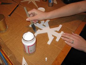 someone is cutting out paper shapes on a table with scissors and paint bottles next to them