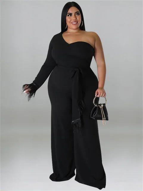 a woman in a black jumpsuit holding a handbag and posing for the camera