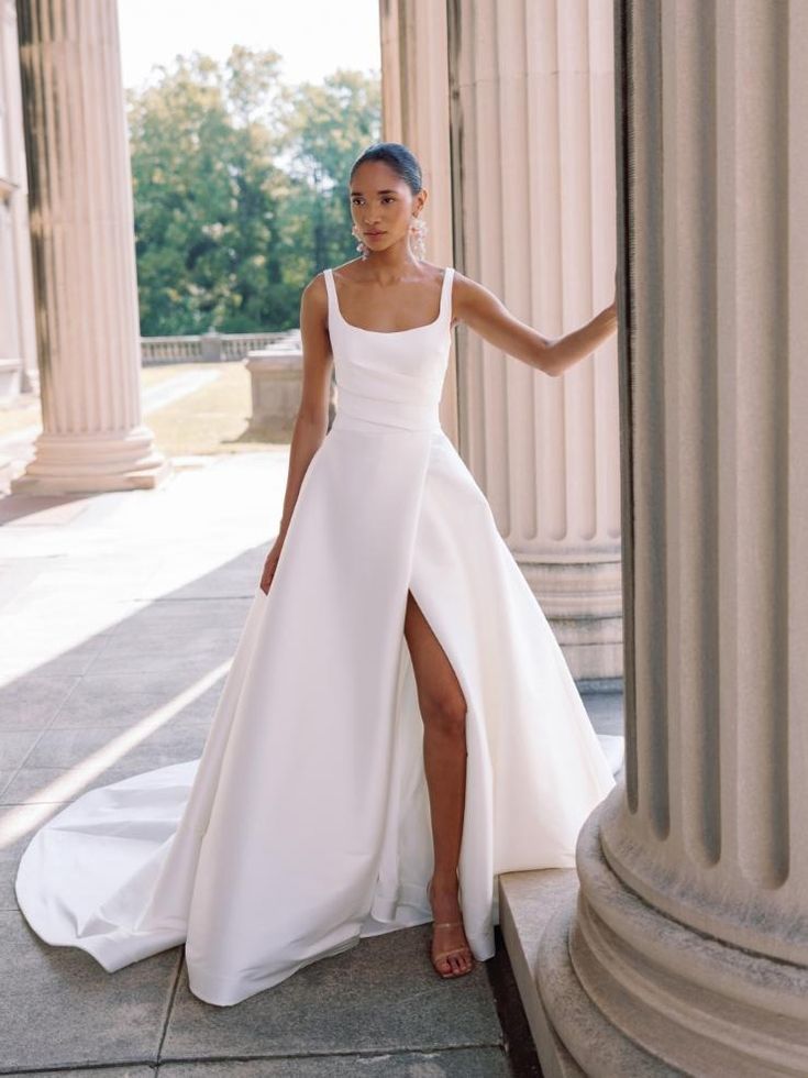 a woman in a white dress standing next to columns