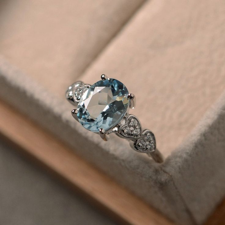 an oval blue topaz and diamond ring in a box