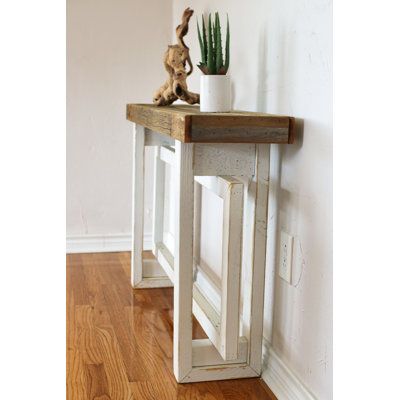 a small wooden table with a potted plant sitting on it's top next to a white wall