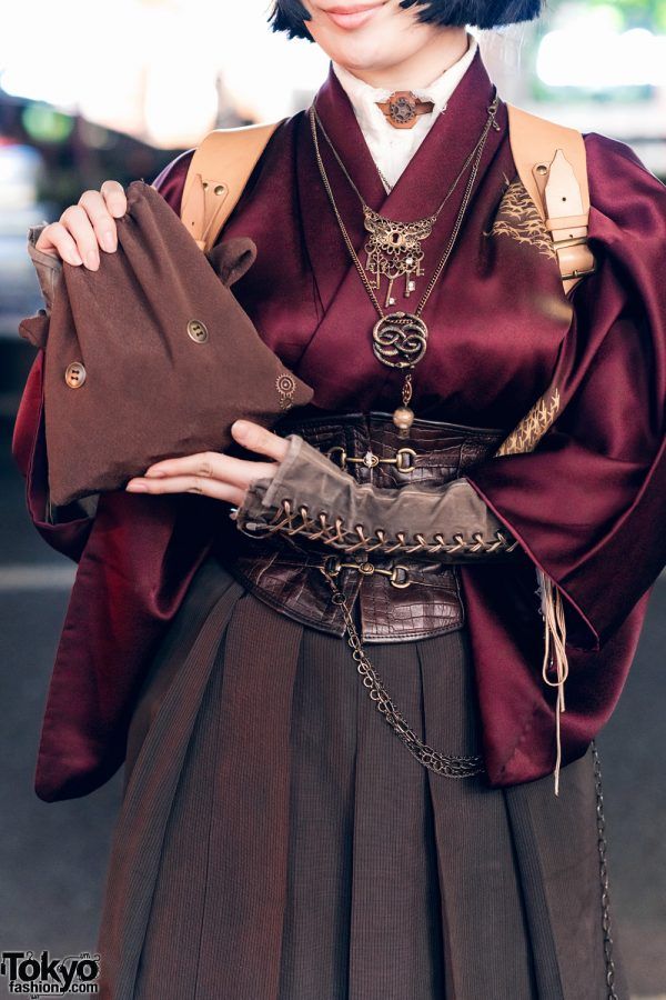 "On the left is Liz, a shoemaking student wearing her grandmother’s maroon silk kimono. She wore it with a white high-necked top and a dark brown hakama skirt, which were cinched with a dark brown leather corset from Excentrique and a harness from Hazy Moon Steamory. Peaking out from her kimono are brown-gray long sleeves with lace-up details. Her accessories include a handmade bag and chain necklaces with large pendants. A pair of black leather boots with high block heels and a black bob..." Steampunk Clothes, Kimono Styles, Solar Punk, Gown Fashion, Mode Costume, Fantasy Stuff, Mode Chanel, Medieval Clothing, Character Inspo