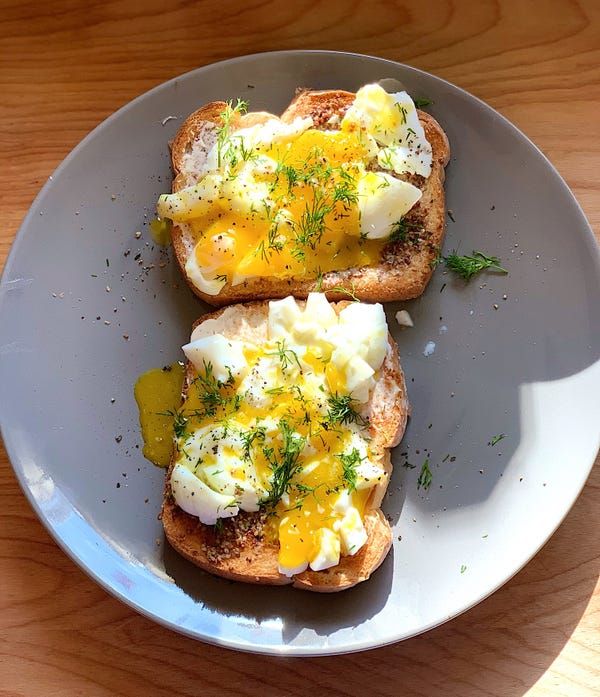 two pieces of toast topped with eggs and herbs