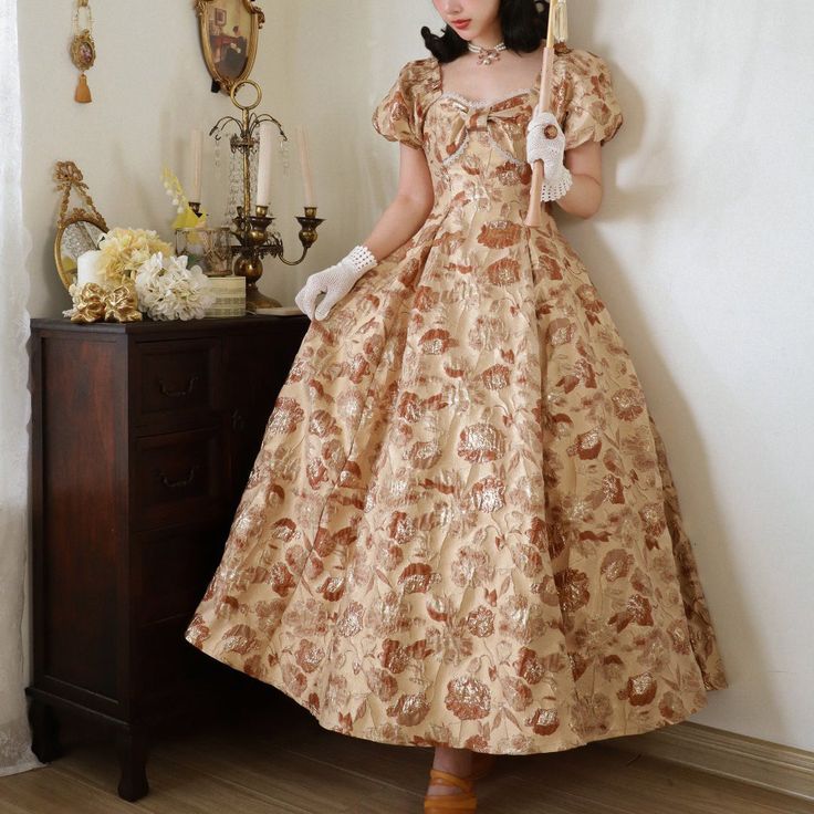 A classic dress depicting tree leaves on a white brown background with golden fabric woven into it. Elegant design with ribbon decoration on the chest. The fabric is thick and sturdy, and the flared skirt gives it an elegant look. She is a noble lady with a gorgeous aura. 
 
 
 Size 
 
 
 
 
 S size 
 
 Length: 129cm 
 Bust: 84cm 
 Waist: 68cm 
 Sleeve length: 22cm 
 
 M size 
 
 
 Length: 130cm 
 Bust: 88cm 
 Waist: 72cm 
 Sleeve length: 23cm 
 
 L size 
 
 Length: 131cm 
 Bust: 92cm 
 Waist: 7 Elegant Gold Dress For Fancy Dress Occasions, Vintage Gold Floor-length Dress, Formal Dresses With Vintage Pattern, Elegant Brown Vintage Dress, Elegant A-line Dress With Vintage Pattern, Elegant Formal Dress With Vintage Pattern, Golden Fabric, Ribbon Decoration, Noble Lady