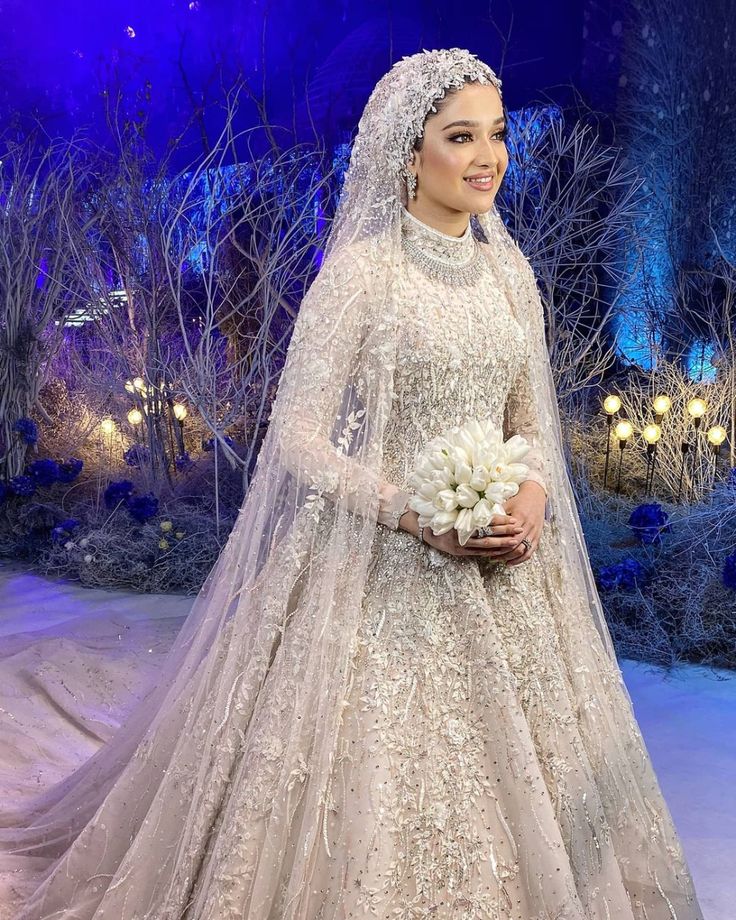 an image of a woman in a wedding dress on the snow with trees and lights behind her